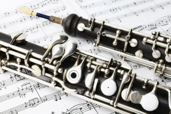 Two black and silver oboes sit on top of sheet music