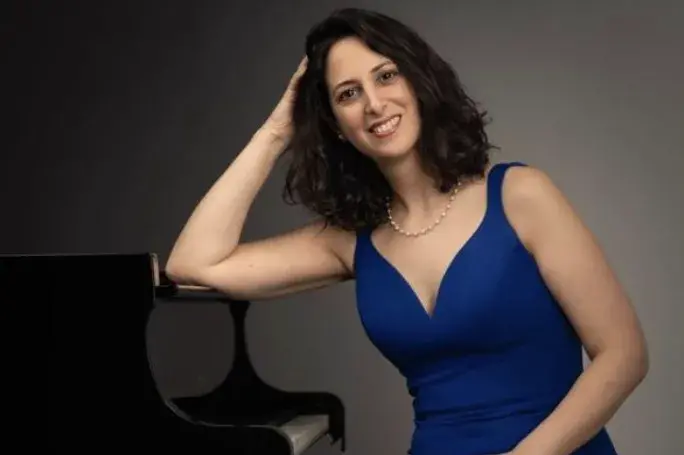 Renana Gutman having her arm on the piano.