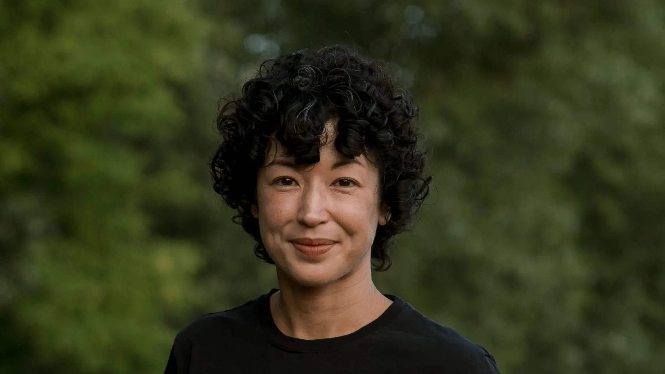 Ellen Tani wears a short sleeved black shirt and white pants and smiles at the camera