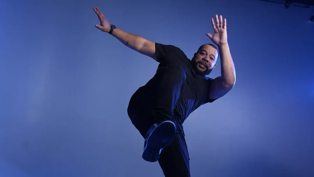 Ryan Johnson dancing in a studio with blue lights and background