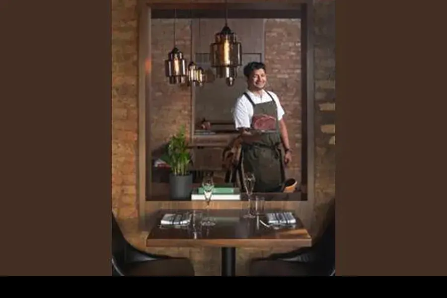 Avishar Barua holds a dish in a restaurant setting.