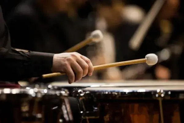 Hand holding a mallet over a drum