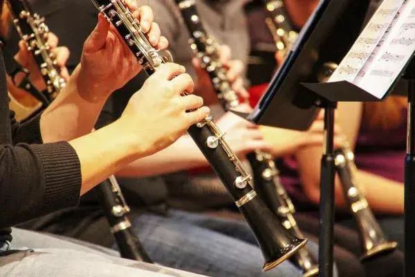 cropped image of people playing black and silver woodwind instruments