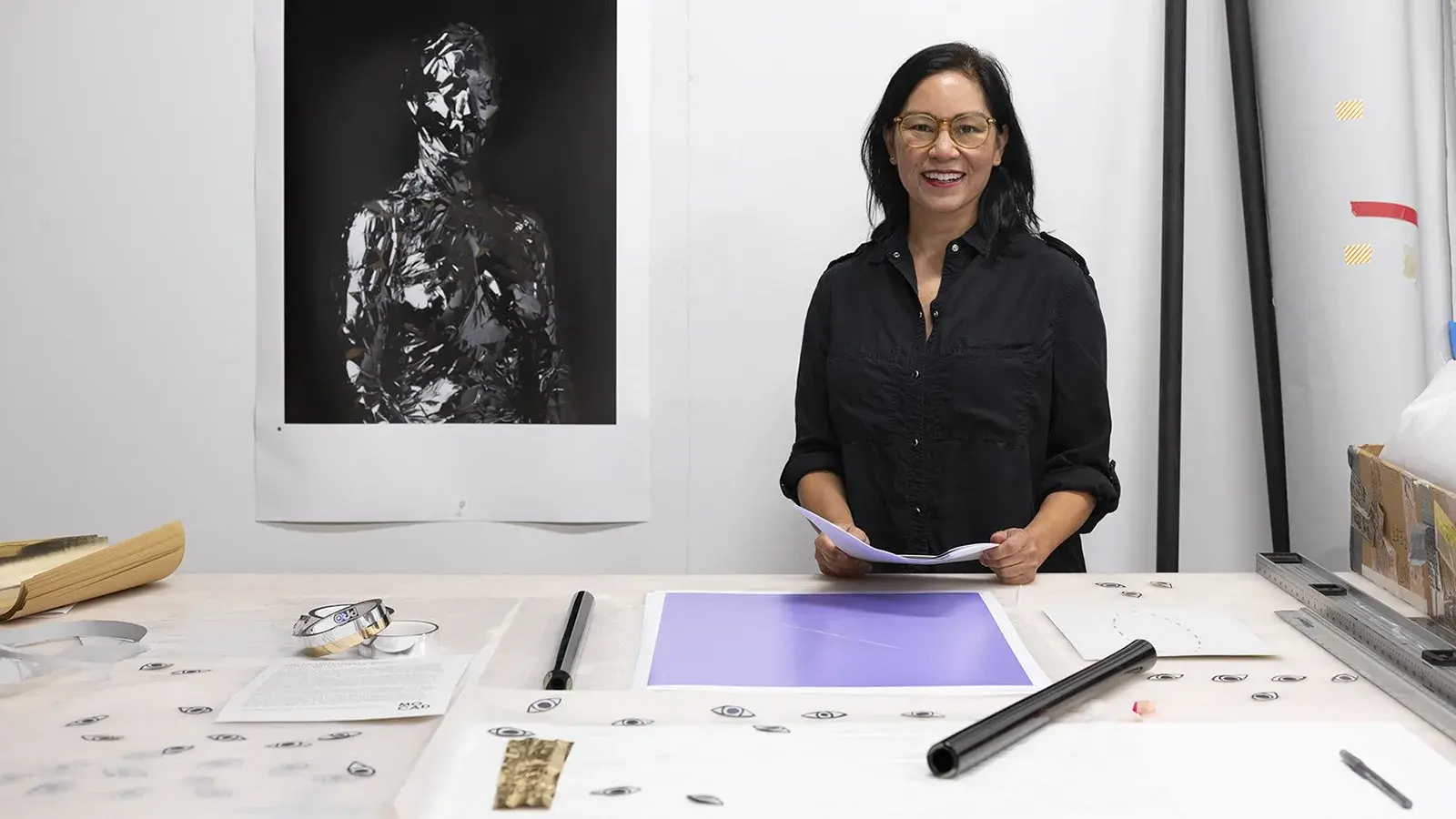 Gina Osterloh portrait looking at camera standing in a studio work space