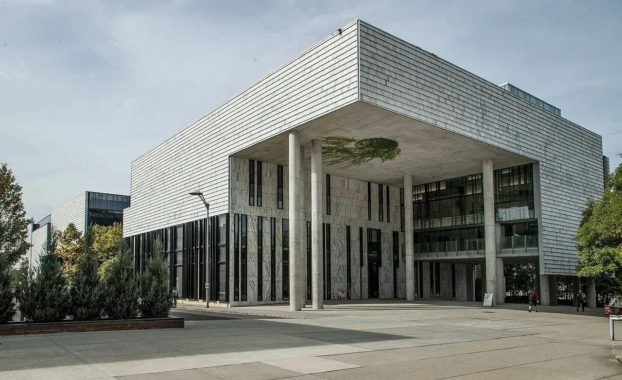 A large building with white and gray marble cladding, tall cylindrical columns and many windows