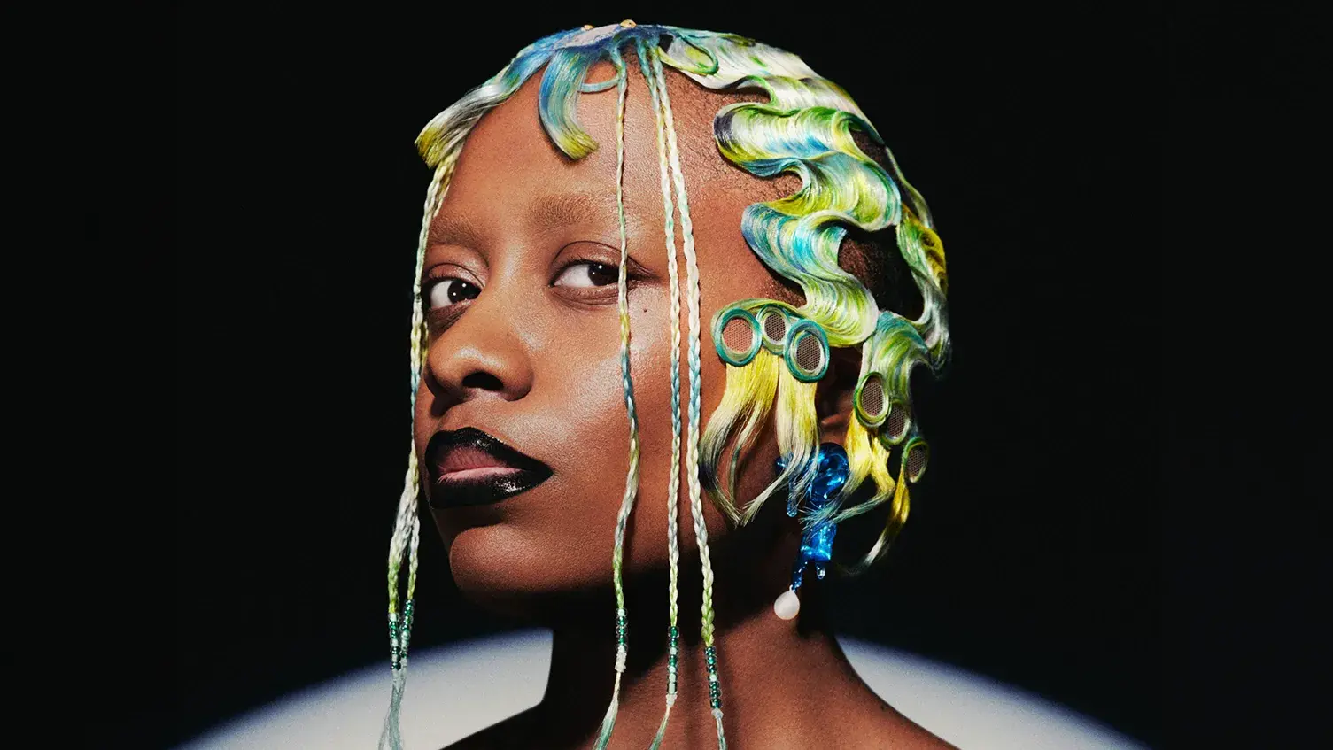 Cécile McLorin Salvant against a black background looking intently at the camera.