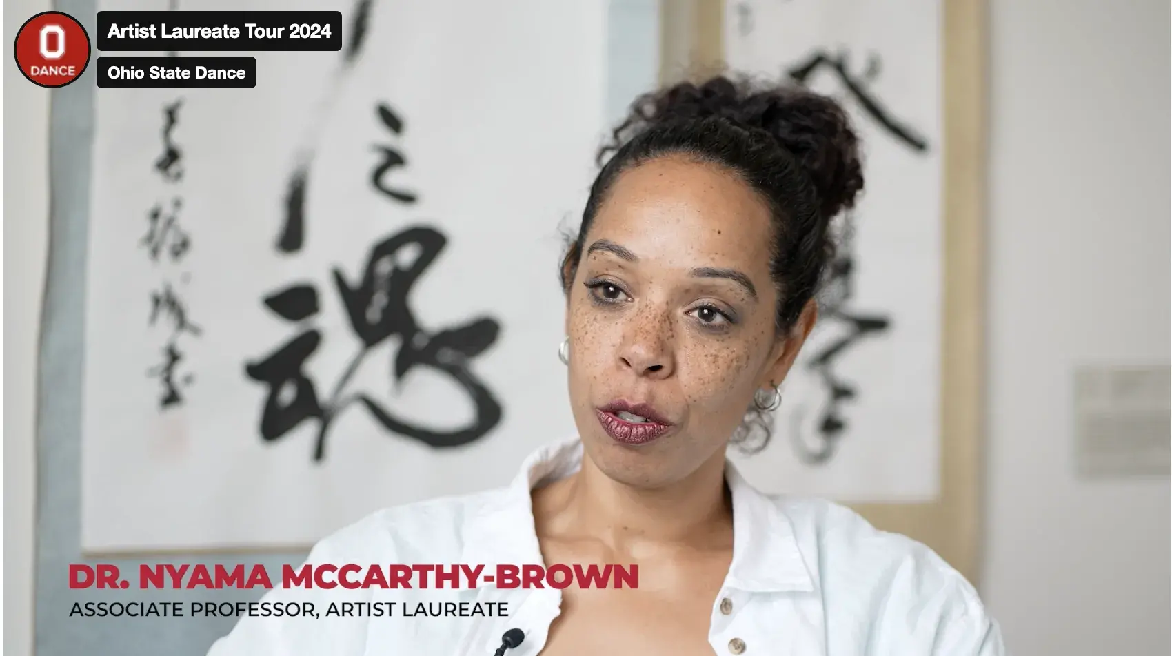 Nyama McCarthy Brown, a Black woman with dark hair, speaks to the camera