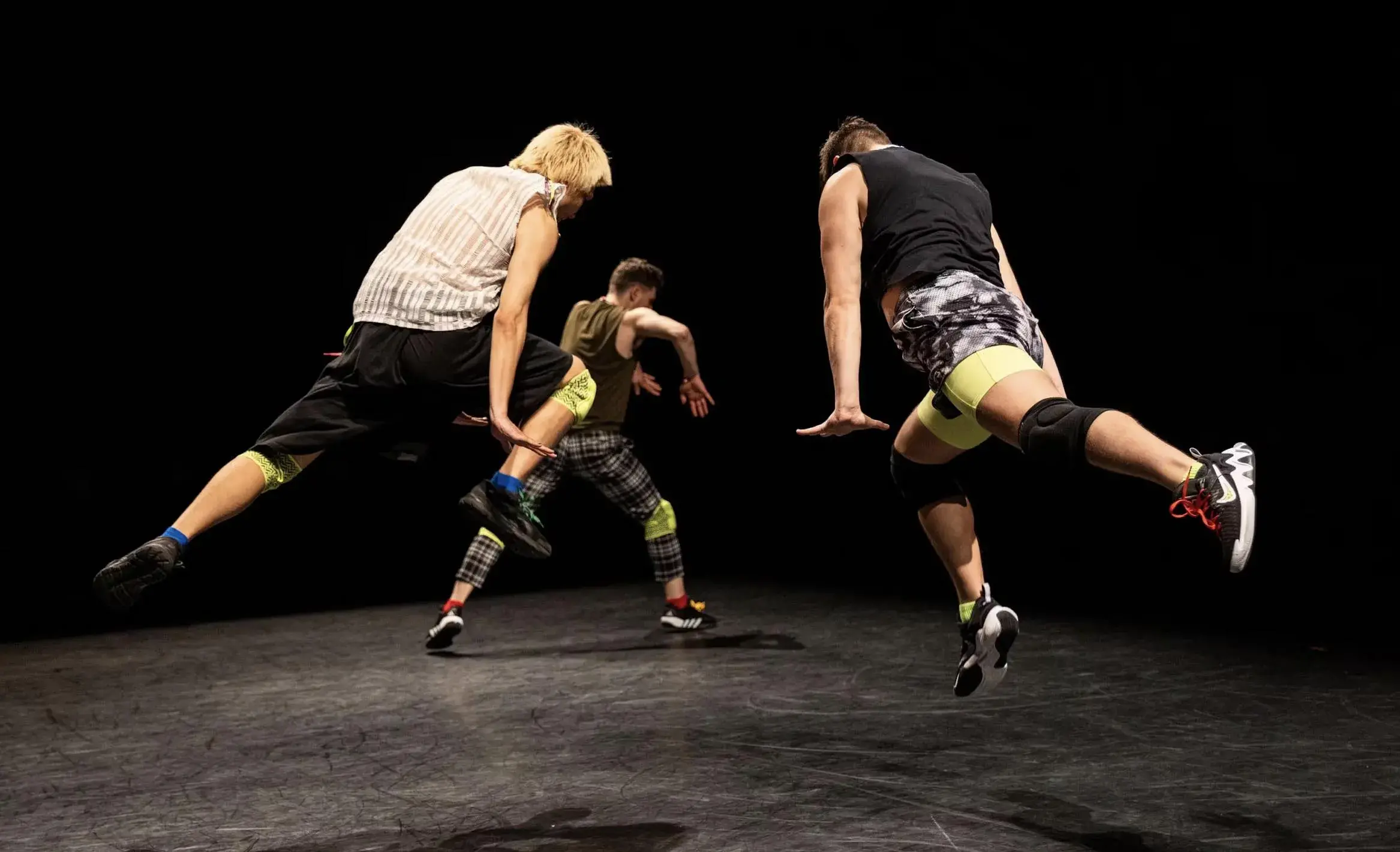 Three dancers wearing black and white on stage