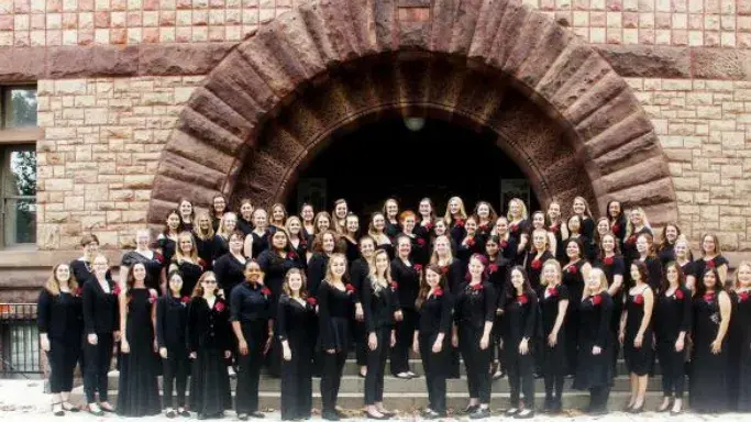 Women&#039;s Glee Club standing in front of a building. 