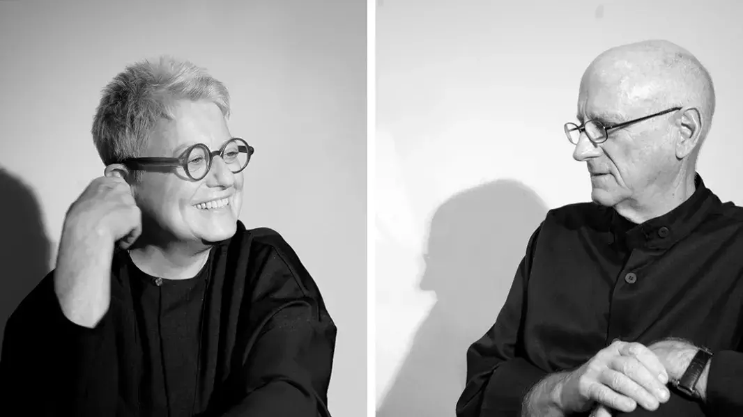 A black and white photo of a woman with short hair and glasses on the left and a man with buzzed hair and glasses on the right