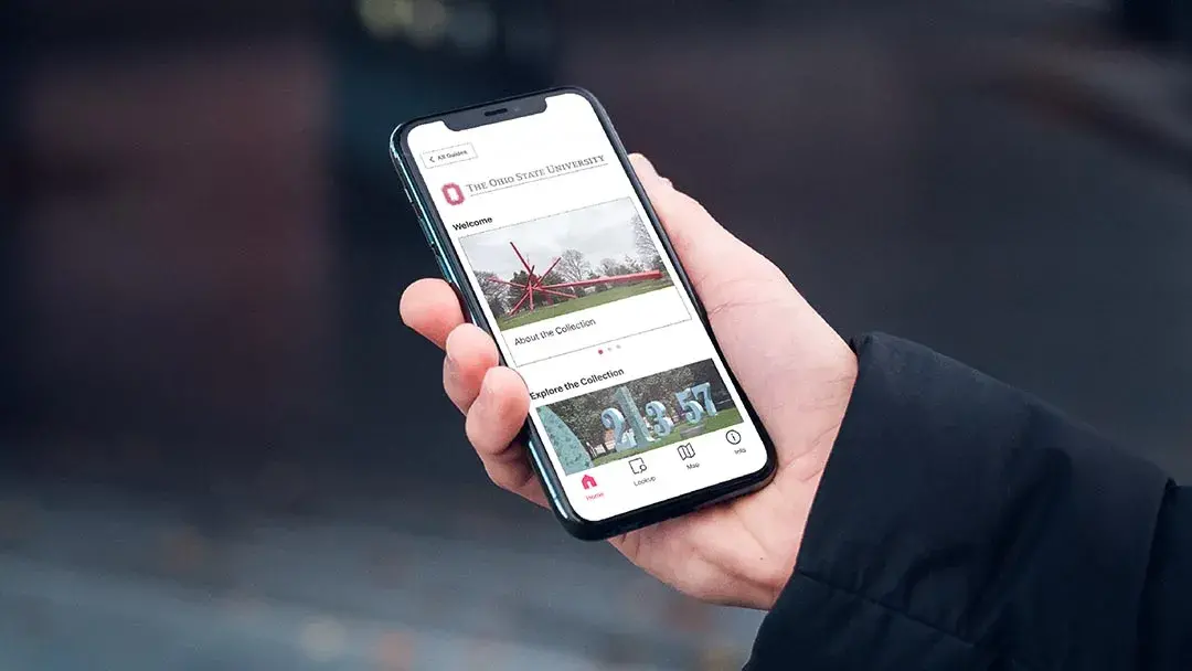 A hand holds a smartphone that displays images of art and The Ohio State University logo