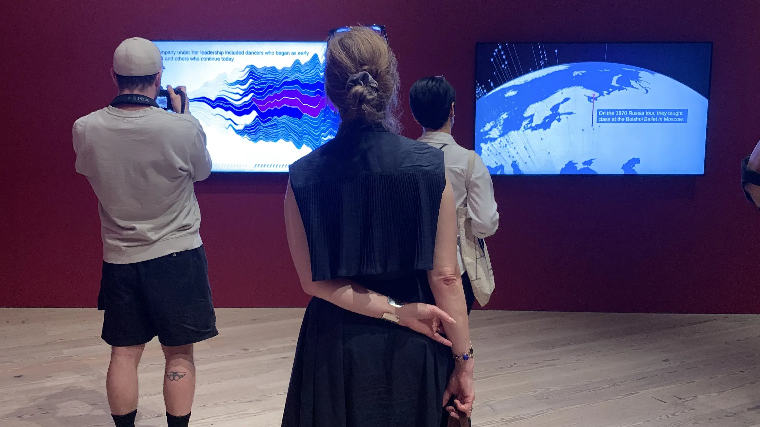 People stand in front of monitors showing images on a wall in an art gallery