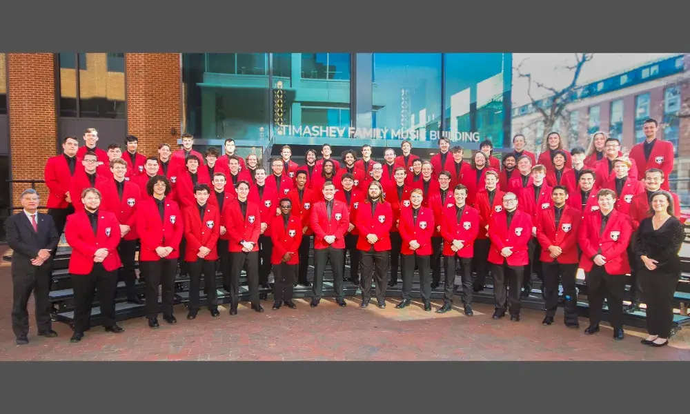 Image of men wearing red jackets and black pants, standing on curved risers