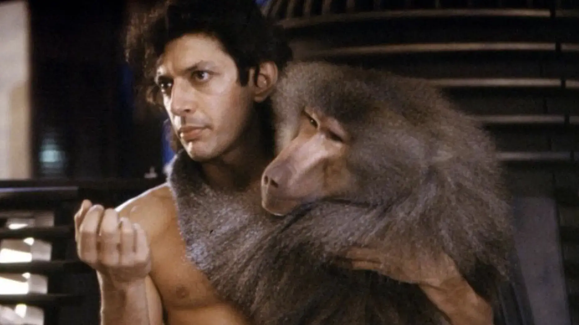 Actor Jeff Goldblum is shirtless and holding a monkey in his arms.