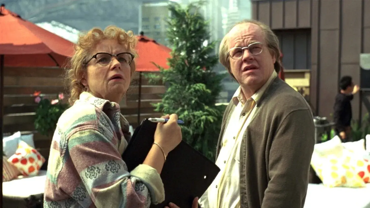 An older woman and man are standing in an outdoor patio area looking up at something.