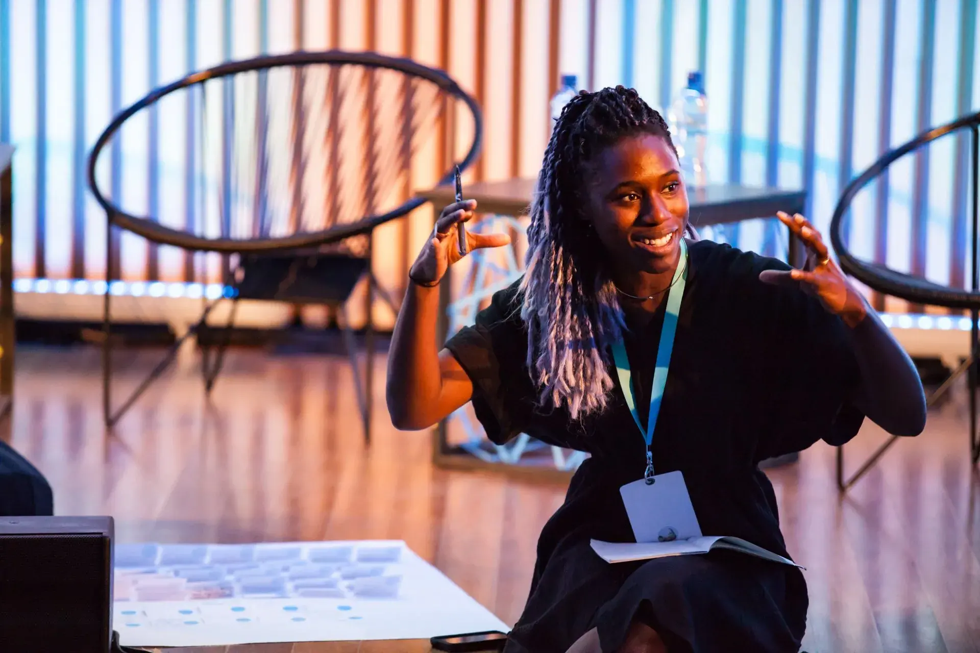 Black woman with braided hair pulled back is gesturing with her hands and smiling