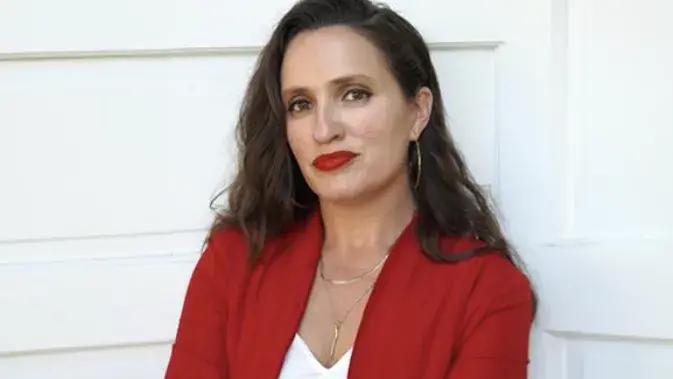 Dr. Jade Power-Sotomayor standing in front of a white building.