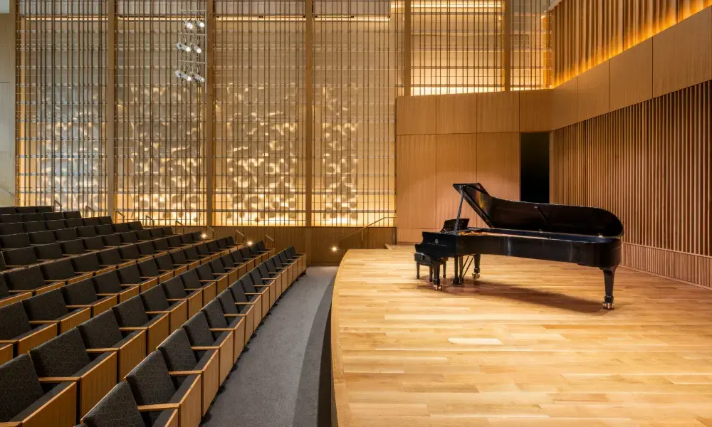 A black piano sits on a wooden stage 