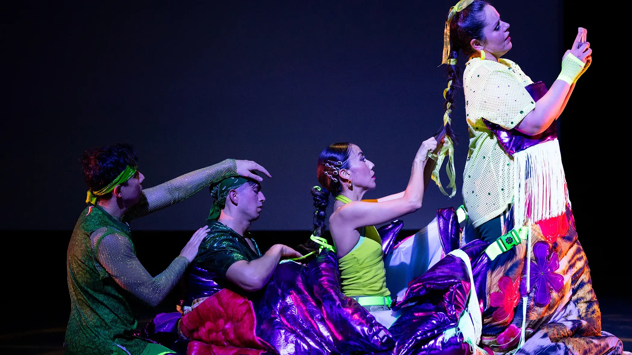 Four people in a line touching or braiding the hair of the person in front of them