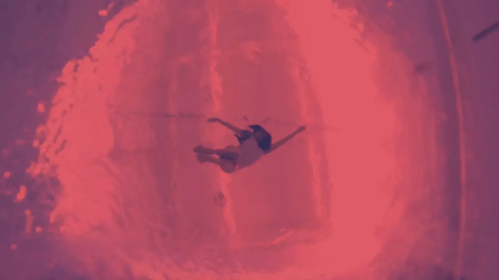 A view from underneath of a person floating in a pool.