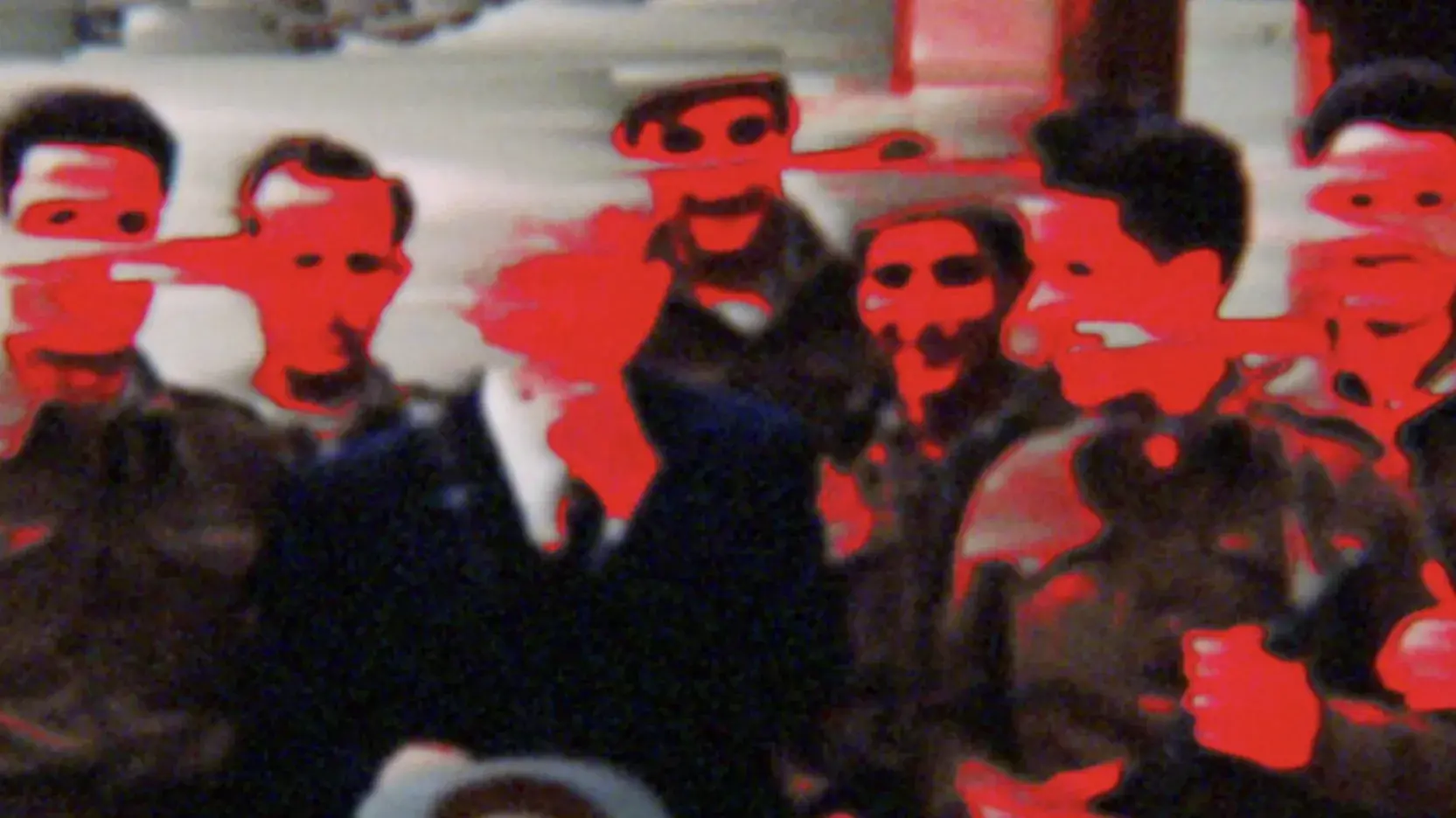 A distorted image of a group of people. Their faces are red and the image is blurred. 