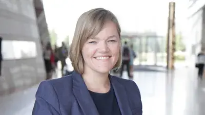 Dr. Jennifer L. Novak-Leonard smiles at the camera and has chin-length blonde hair and wears a blue blazer