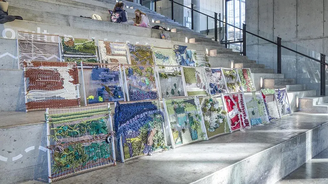 Small looms with woven yarn on them sit on large concrete stairs