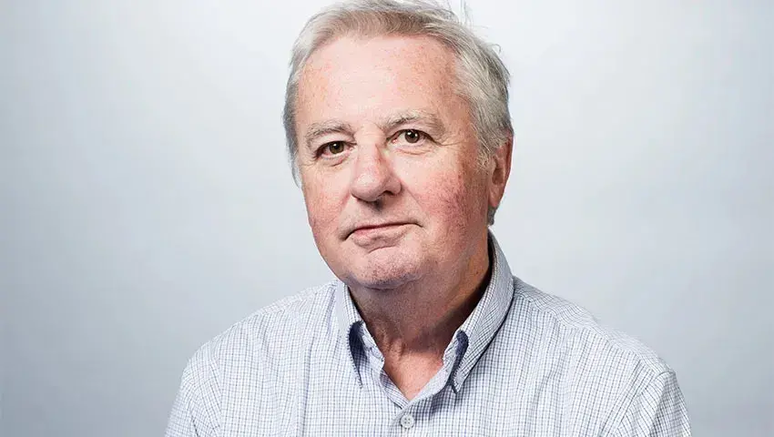 Bill Horrigan, a white man with gray hair, wears a button-down shirt and slightly smiles at the camera
