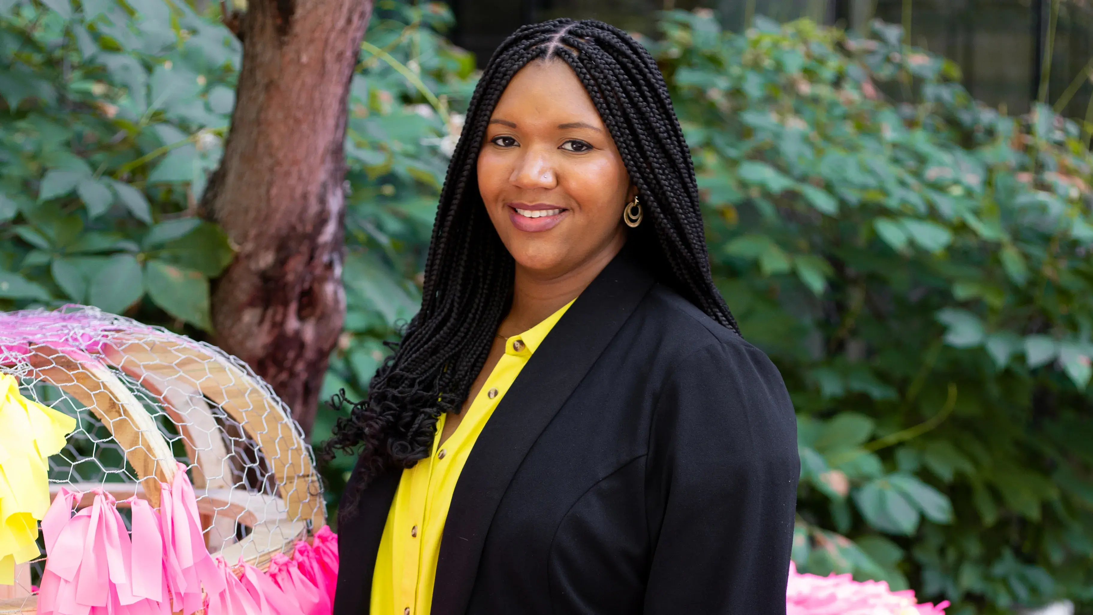 Tameka Baba stands with two pink round sculptures, one of which is only partially completed