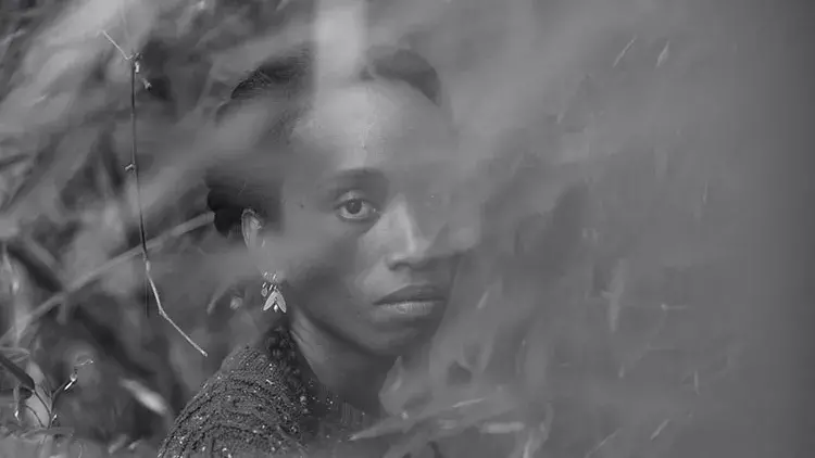 Dionne Lee stands in a field of tall grasses, partially obscured by them