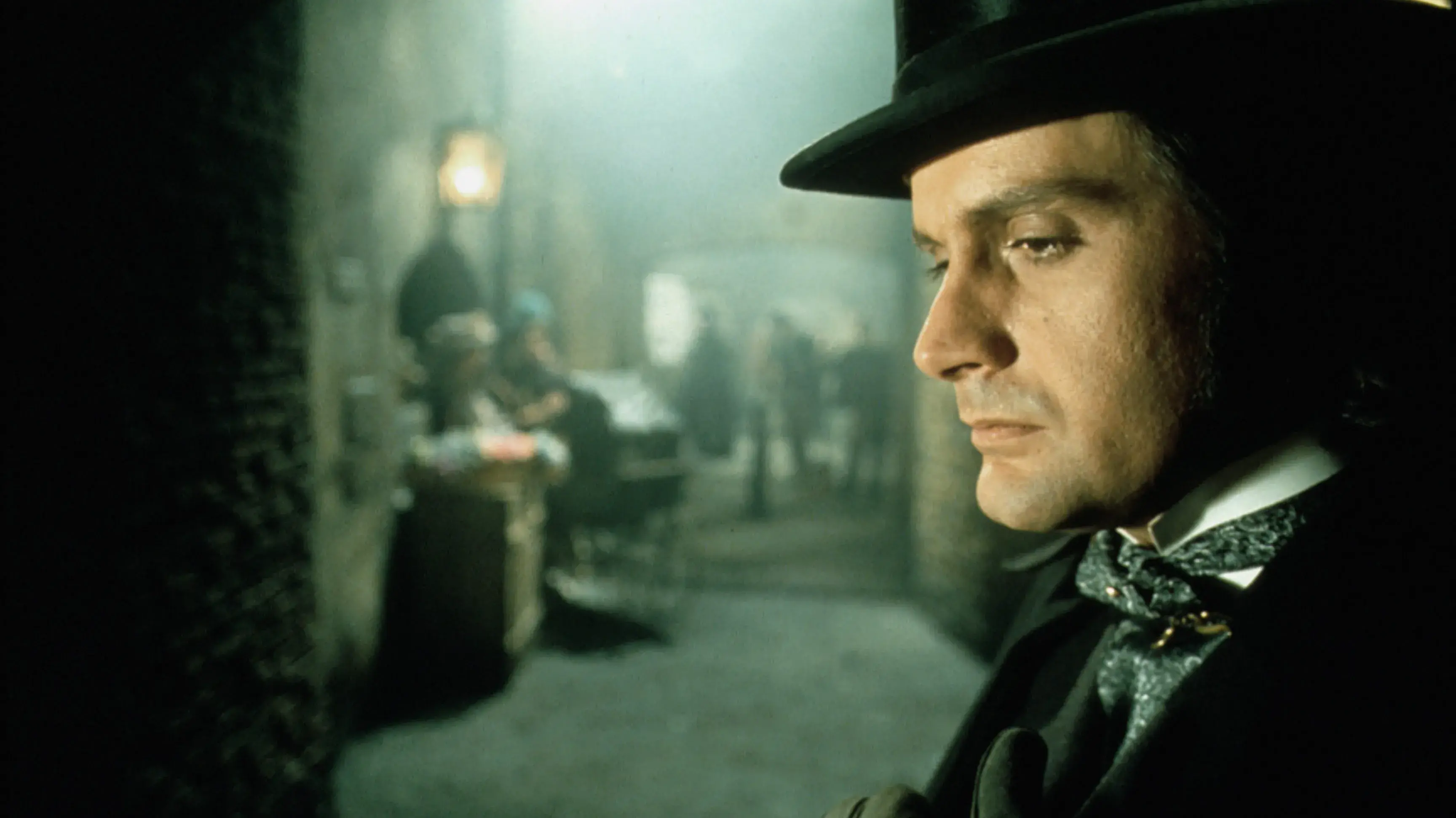 Closeup of a man wearing a top hat and standing in an alley.