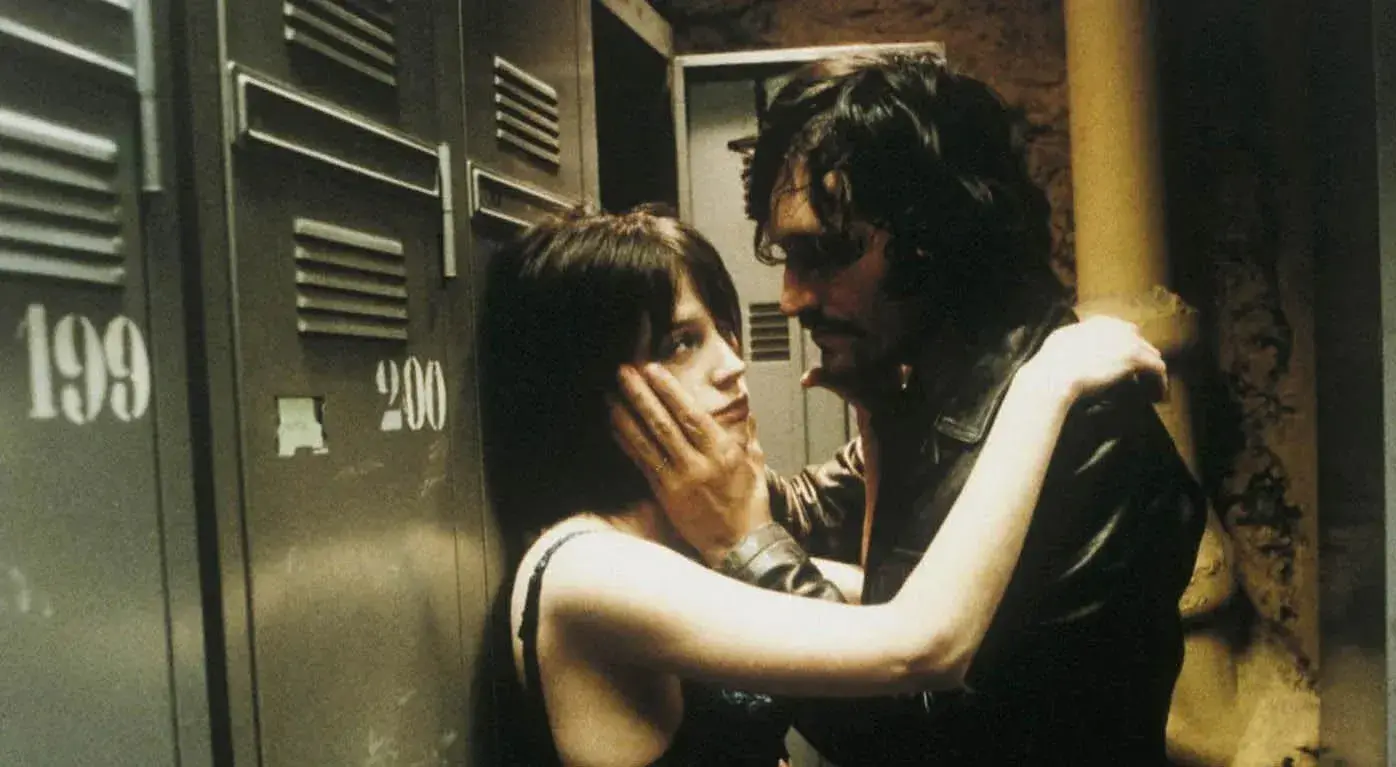A woman and a man are embracing standing in front of metal lockers