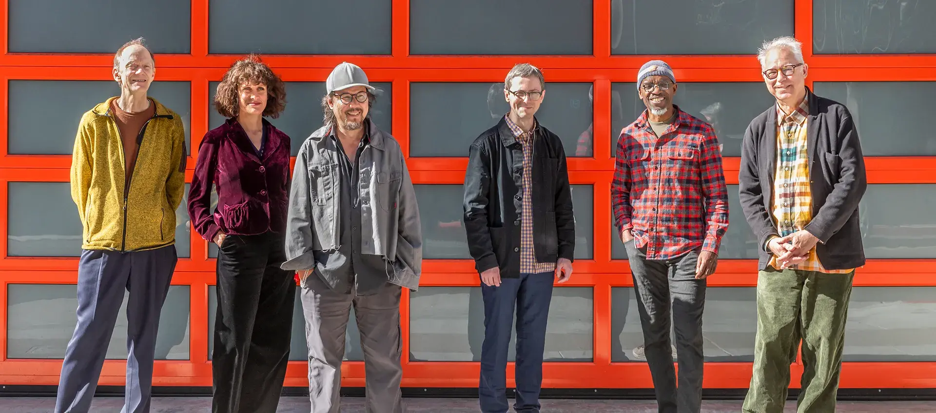 Six people stand in front of an orange grid background