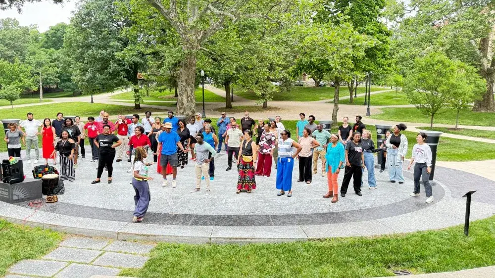 A group of people stand in a plaza facing an instructor