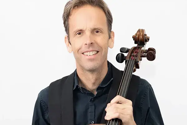 Gregory Sauer holding a cello.