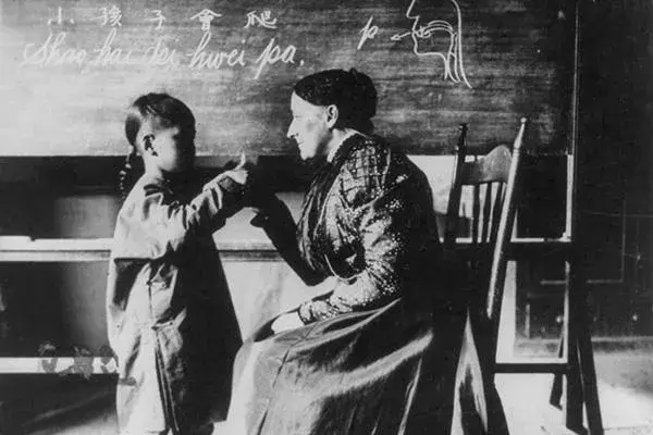 Black and white image of a young person being taught by an older person.