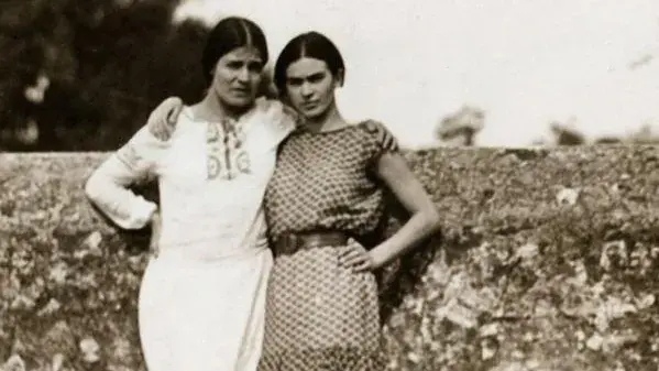 Black and white image of two women standing in a field with their arms around each other's shoulders