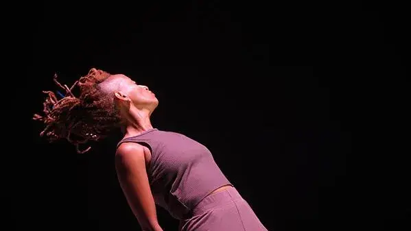 A woman dances and looks away from the camera