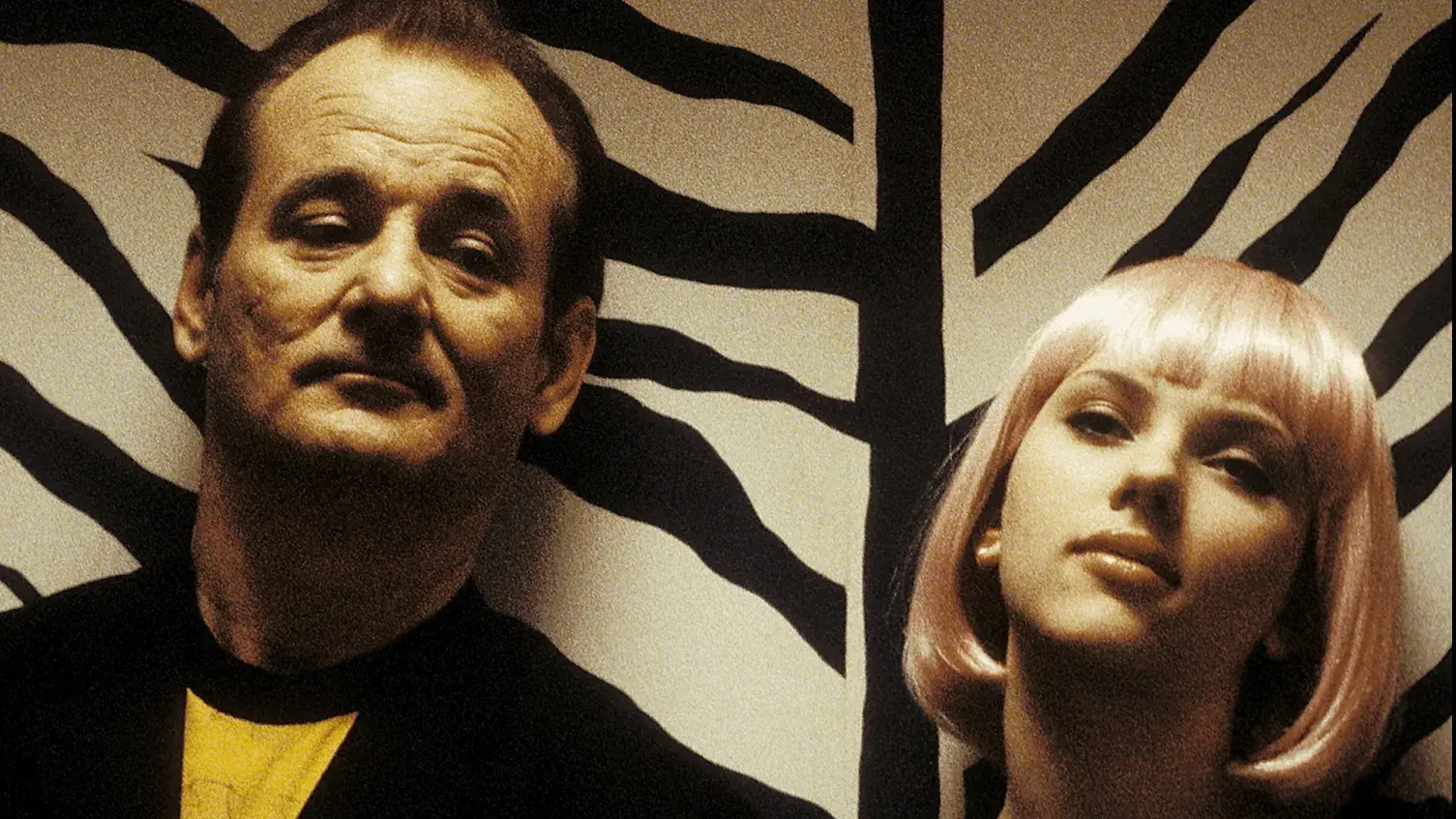 Bill Murray and Scarlett Johansson stand in front of a tiger striped wall.