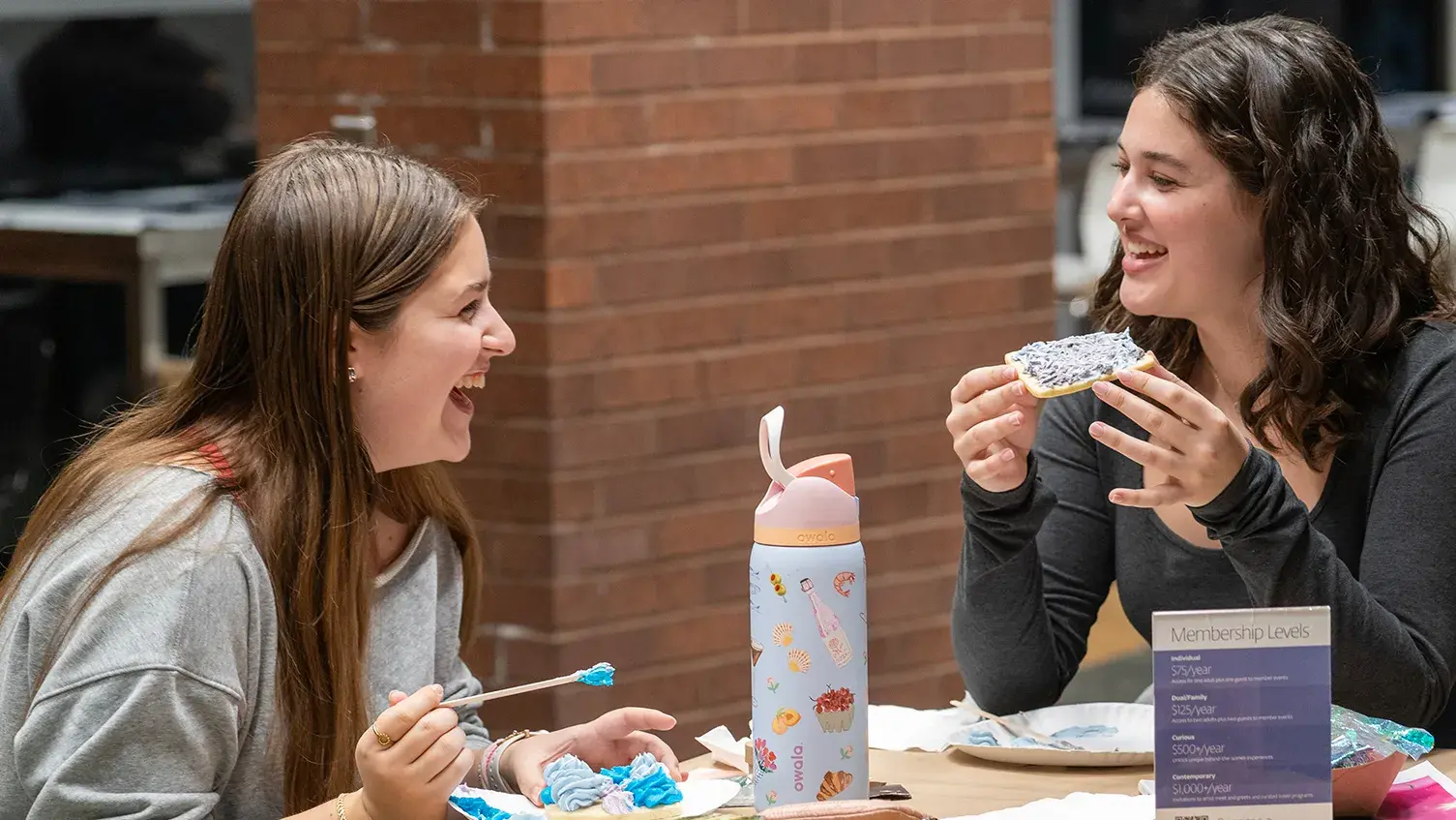 Two young adults sit in Heirloom Café with cookies they decorated.