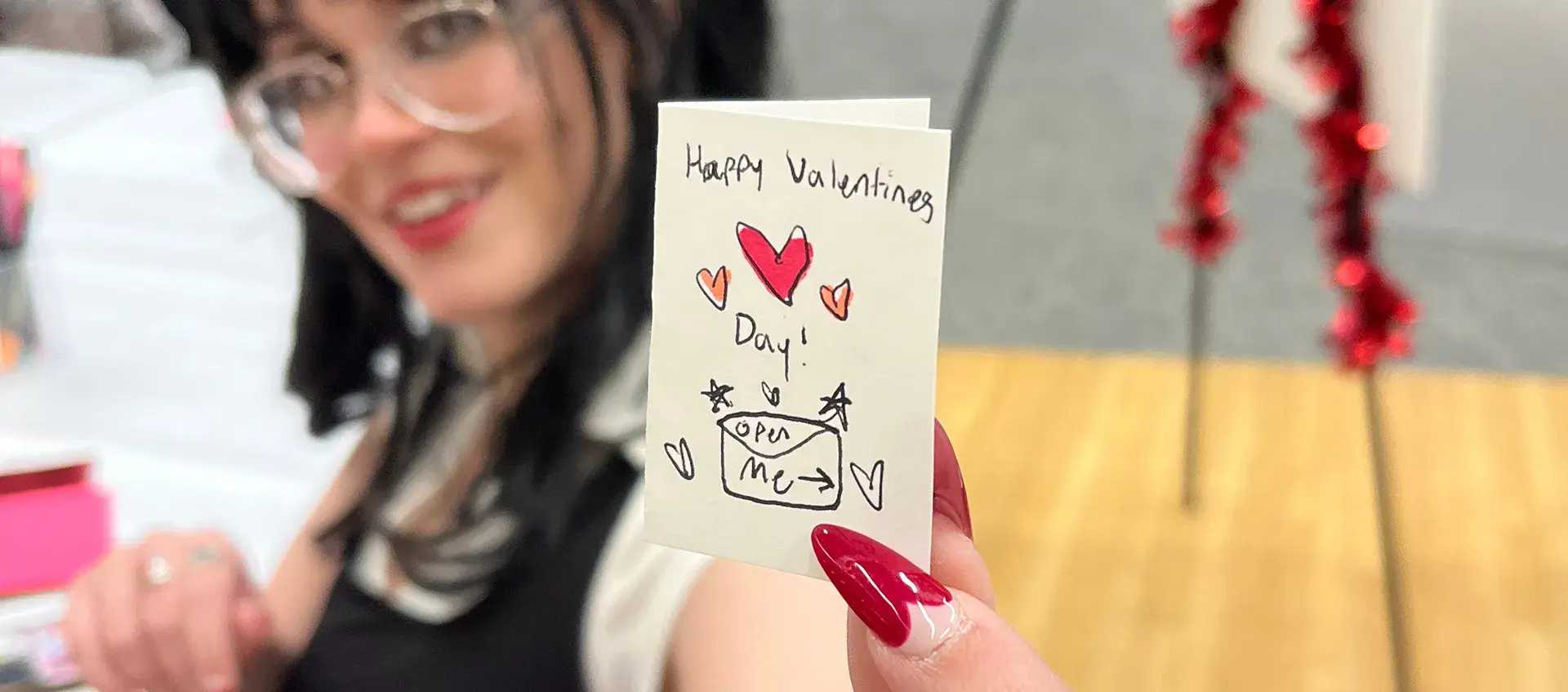 Someone holds a card with hearts on it towards the camera