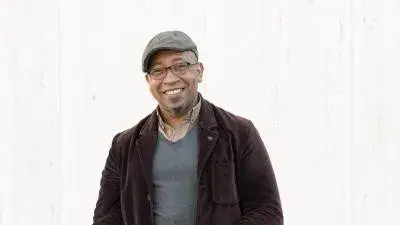 Charles O. Anderson smiles at the camera. He is a Black man and wears a cap and glasses.