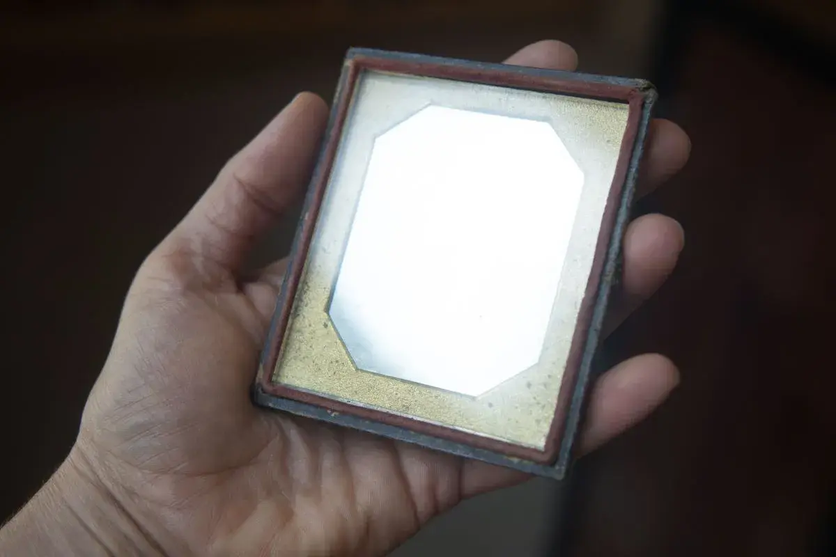 A hand holds a small vintage photo frame