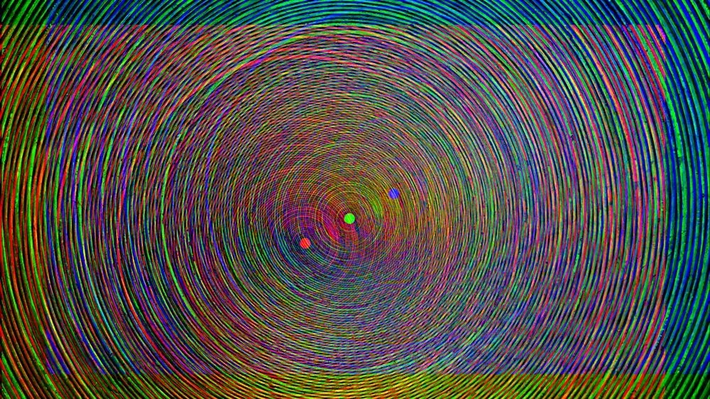 Multicolored image of many concentric circles with three small dots in the center in red, green, and blue
