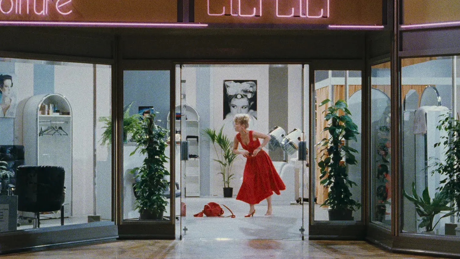 A mall storefront with woman in a red dress standing in the doorway.