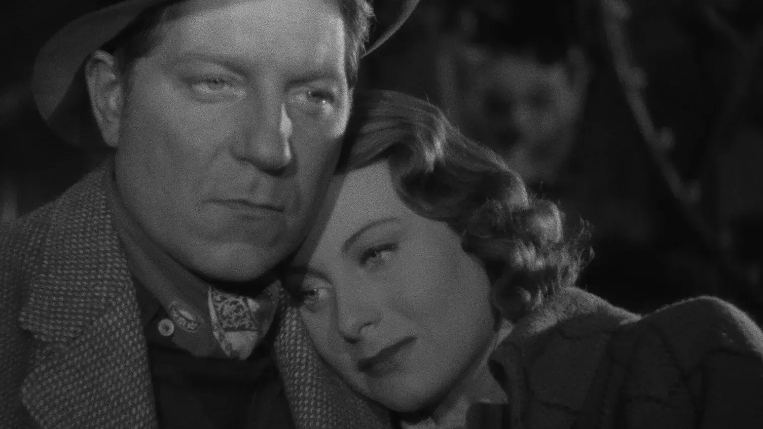 Black and white image of a woman leaning on a man's shoulder.