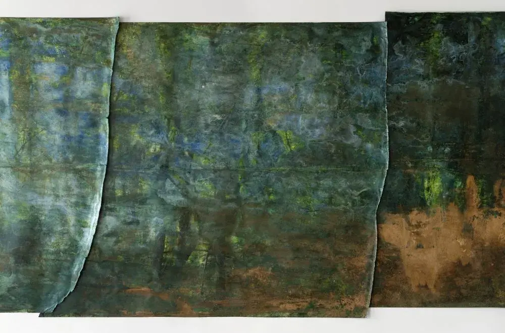 Close-up detail of artwork made of overlapping panels with ripped edges, with various shades of greens and browns