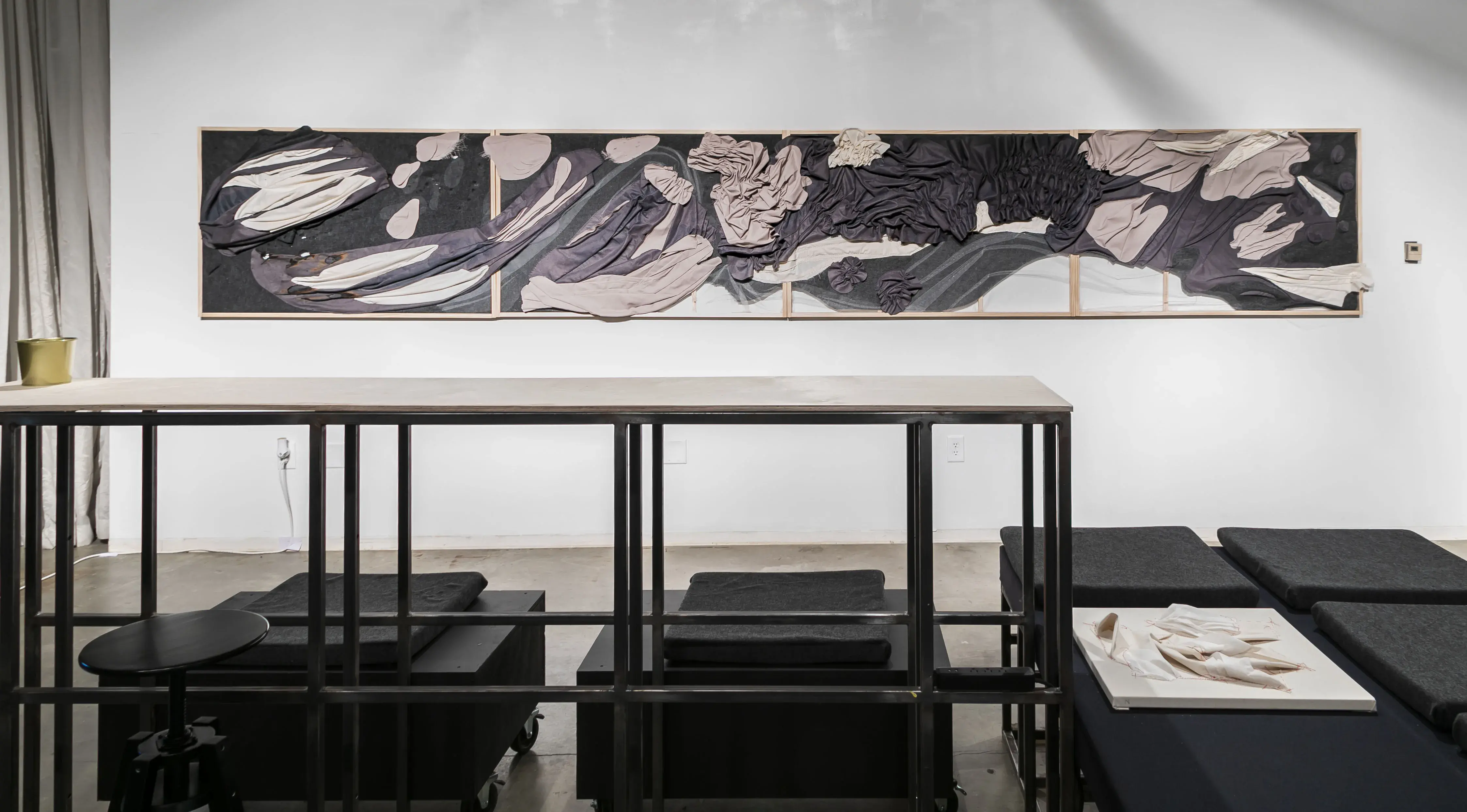 Long grayscale abstract artwork on the wall behind several tables and cubes