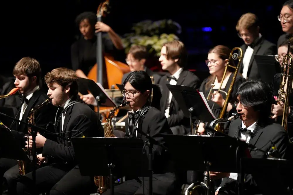 Young people playing musical instruments on a darkened stage