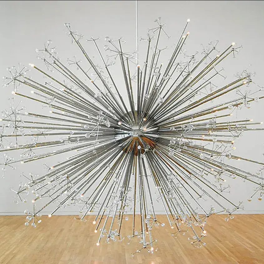 Large round metal and glass sculpture on one side and a room with many images on the wall on the other